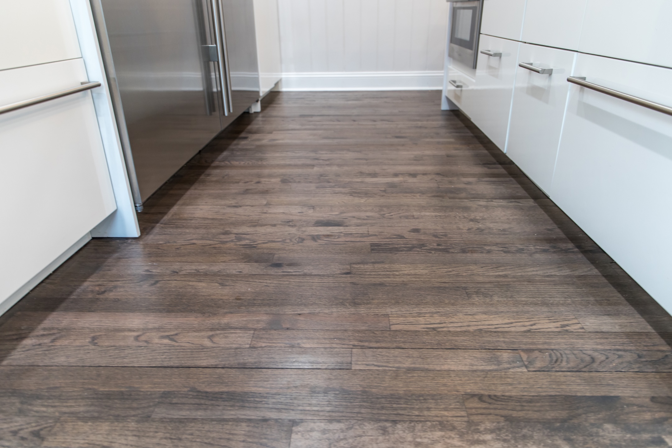 Dark wood hardwood floors in a newly renovated white cabinet modern kitchen.